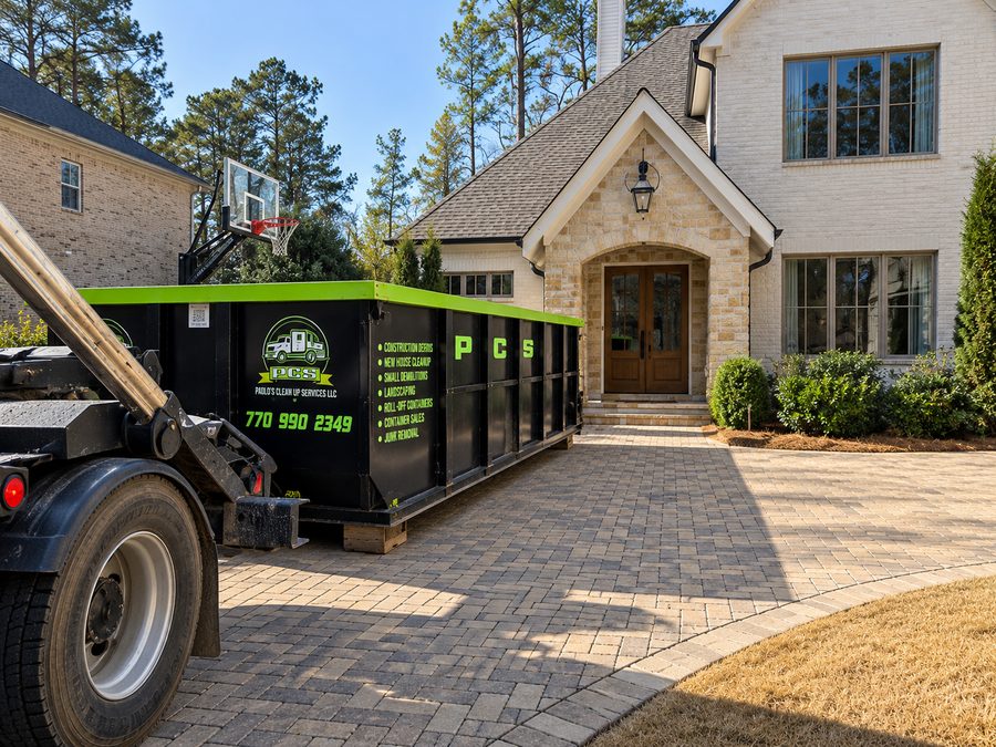 Roll-off container being placed in the driveway of a large residential home